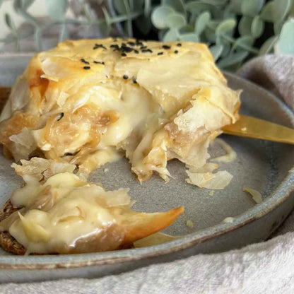 Queso camembert con cebolla caramelizada envuelta en crujiente masa filo. Ideal para un rico picoteo.